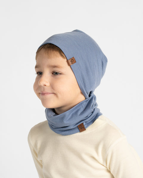 Three-quarter angle portrait of a boy looking to the side, wearing a dusty blue beanie and matching neck gaiter.