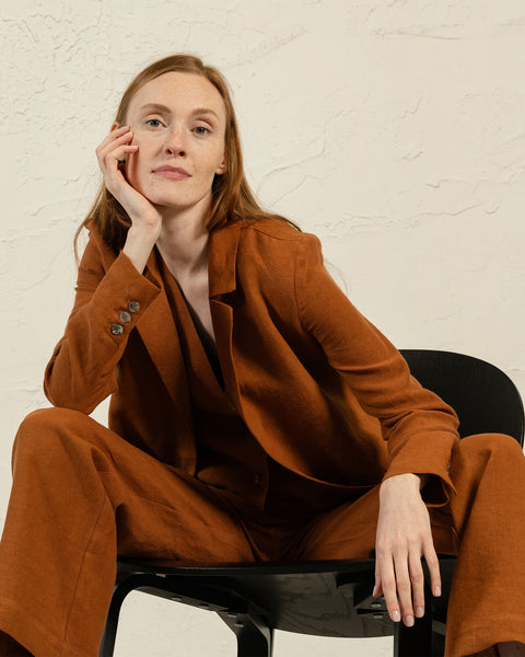 Elegant linen blazer Quin in rust brown shown on seated model, featuring notch lapels and classic fit by menique