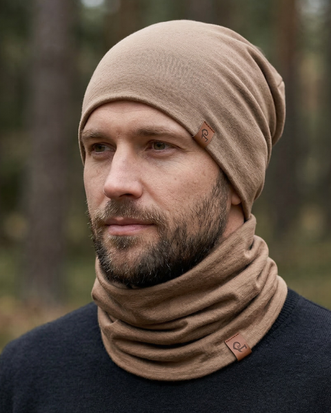 Man wearing beige merino wool beanie and neck gaiter outdoors, lightweight breathable merino accessories for cold weather.