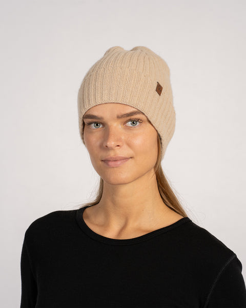 Unisex ribbed beanie in creamy beige, knitted from Merino wool and cashmere, shown front view on a model with neutral expression.