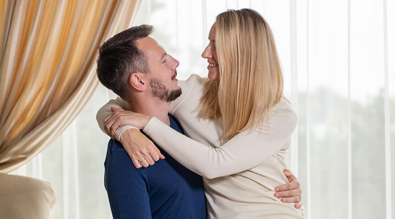 In the photo you can see couple hugging. They are both wearing long sleeve sweaters made from soft and organic 100% Merino Wool. Woman is wearing natural color crewneck, while man is wearing dark blue one,