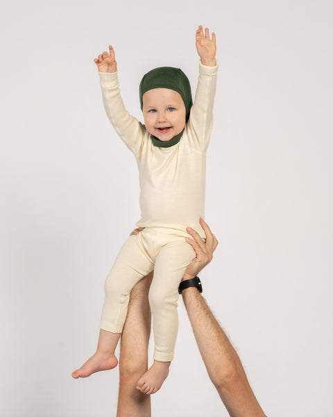 Happy toddler being held up. Toddler is wearing merino wool set and balaclava.