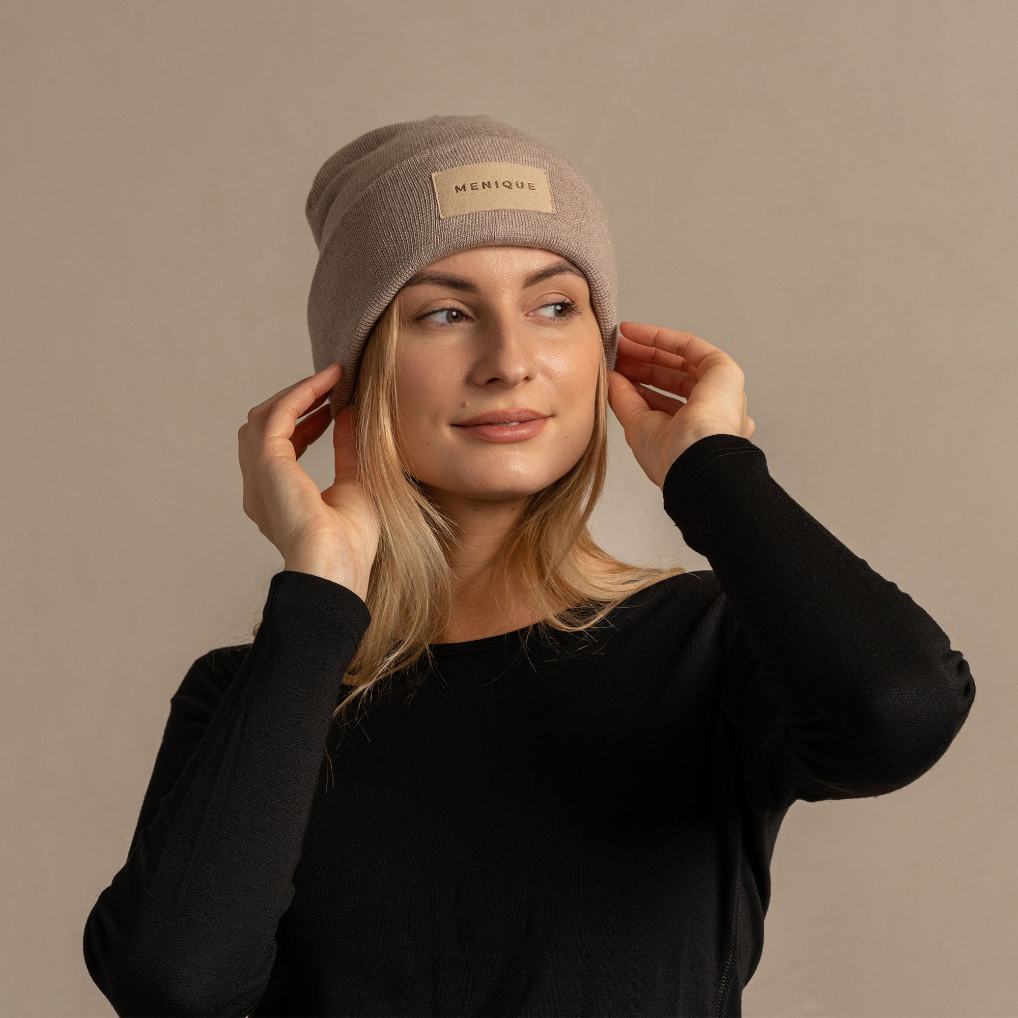 Woman wearing merino wool long sleeve top and knitted merino wool beanie with MENIQUE logo