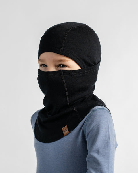 Three-quarter portrait of a child wearing a black balaclava pulled up over the nose and mouth, showing only the eyes.