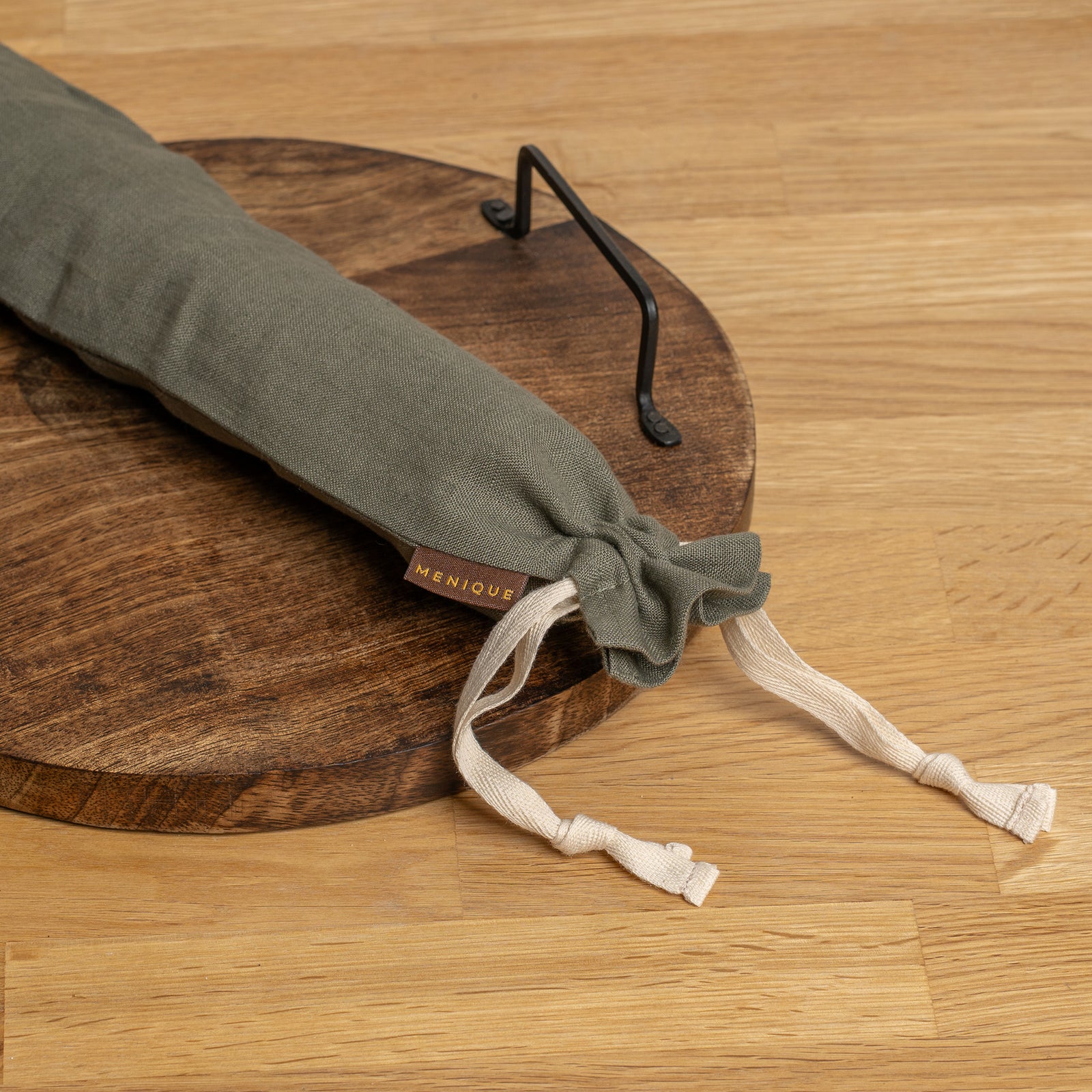 Long Bread bag hanging on a hook with bread and kitchen items on a table.