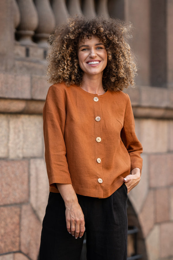 Woman with curly hair wearing almond brown linen jacket Alice and standing in  astreet