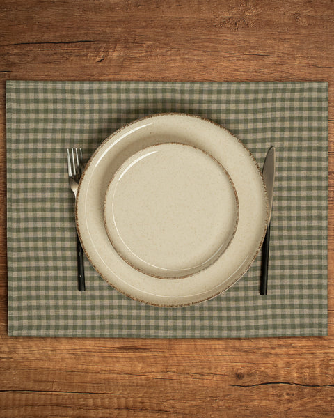 The menique linen placemat in green check color on a wooden table top.