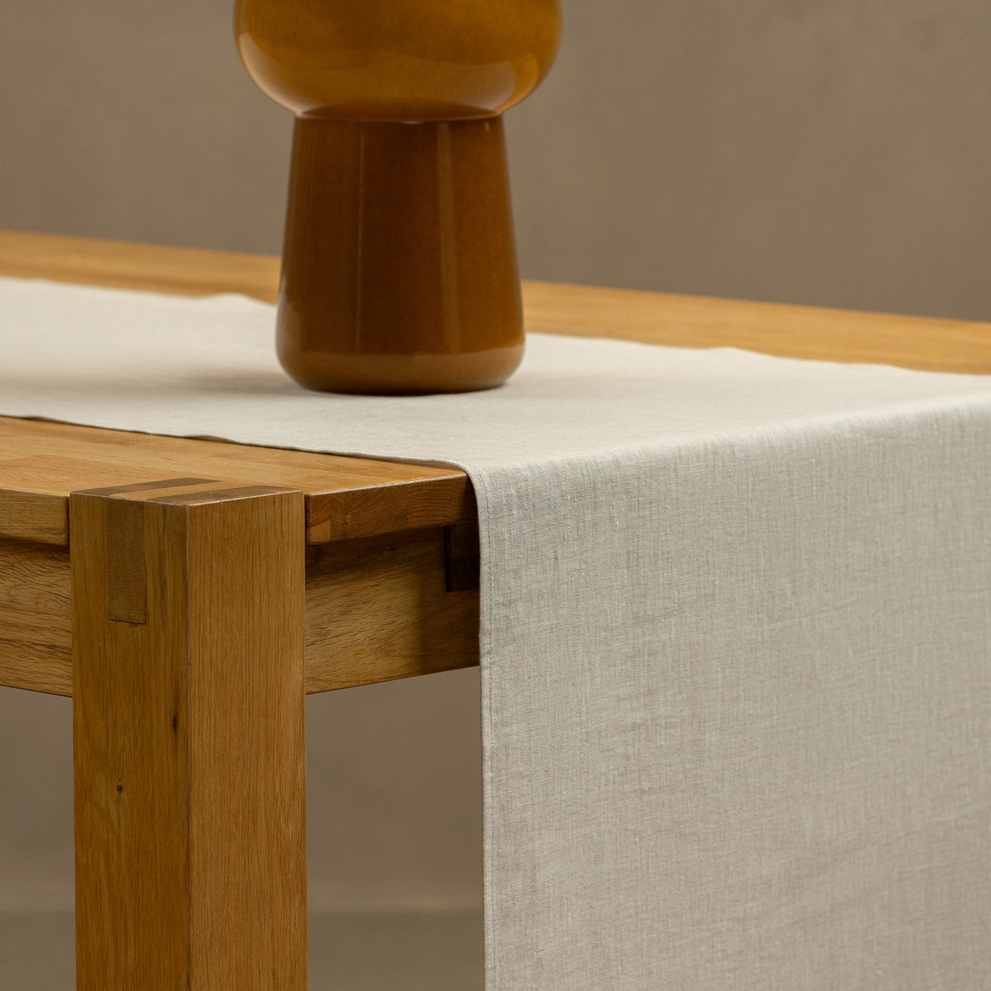 The menique natural linen table runner on top of a green check tablecloth. 