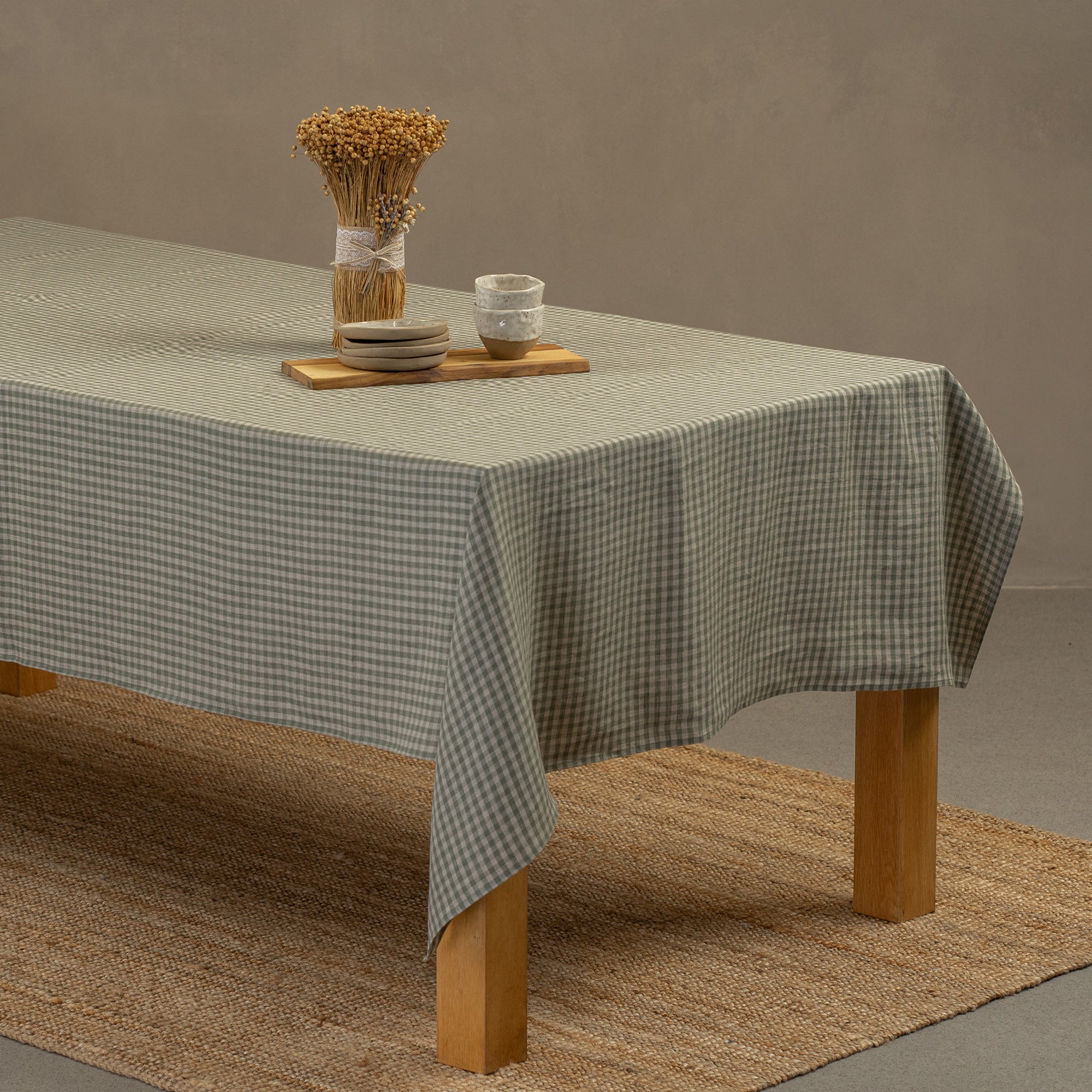 A cinnamon red linen tablecloth on a rustic autumn season wedding table. It has seasonal centerpieces on top and matching color linen napkins on top of the plates.