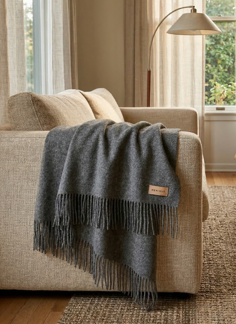 Soft gray wool blanket draped over beige sofa in cozy modern living room interior
