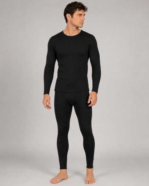 A full-body studio shot of a barefoot man looking to the side, wearing a fitted black long-sleeved thermal shirt and matching black thermal leggings.