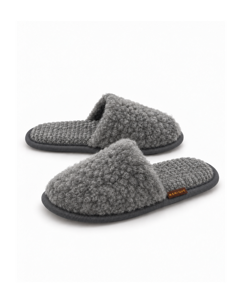 A pair of dark gray, fuzzy, slip-on style slippers with a textured footbed and a small brown "MENIQUE" tag.