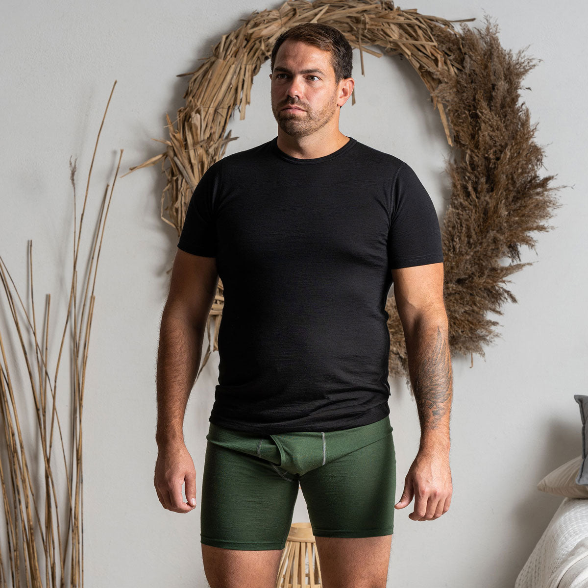 A man wearing the menique men's boxer underwear in color dark green.