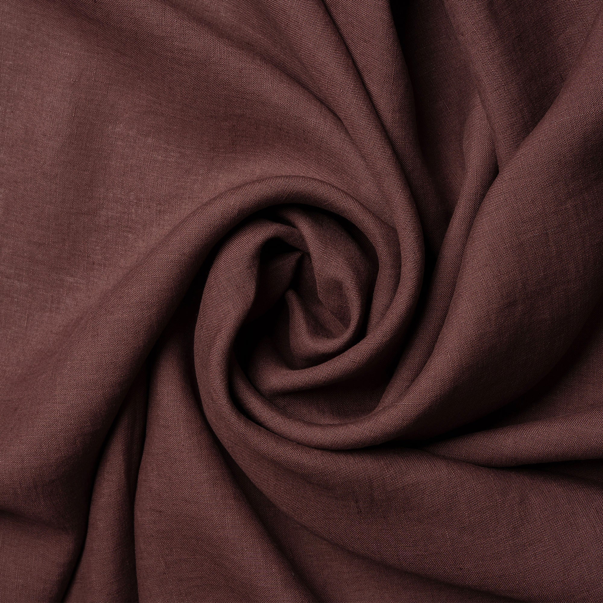 A cinnamon red linen tablecloth on a rustic autumn season wedding table. It has seasonal centerpieces on top and matching color linen napkins on top of the plates.