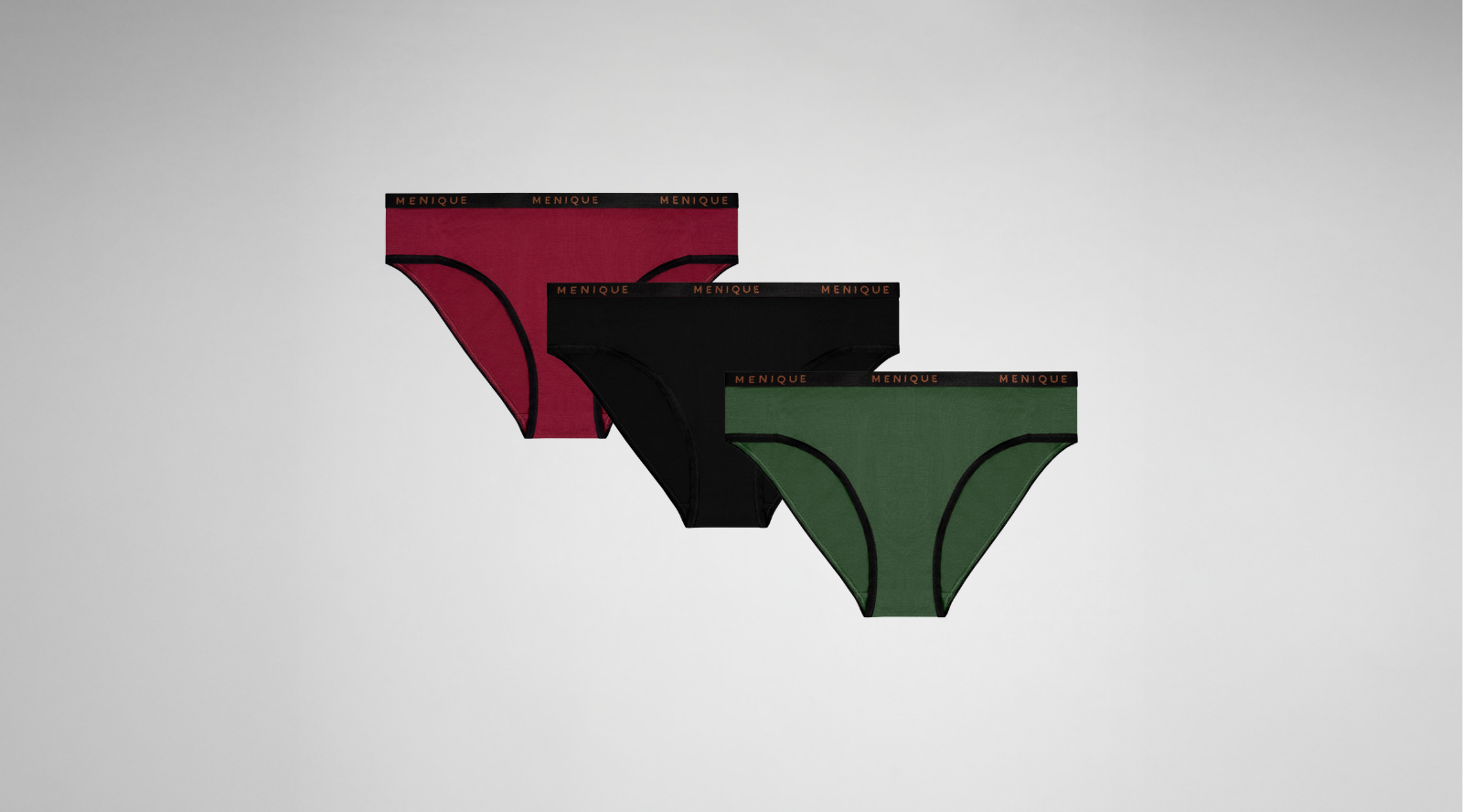 A three-pack of women's bikini underwear in deep red, black, and dark green is arranged diagonally against a light gray background. Each pair features black trim along the leg openings and a matching black elastic waistband displaying the brand name "MENIQUE" in copper lettering.