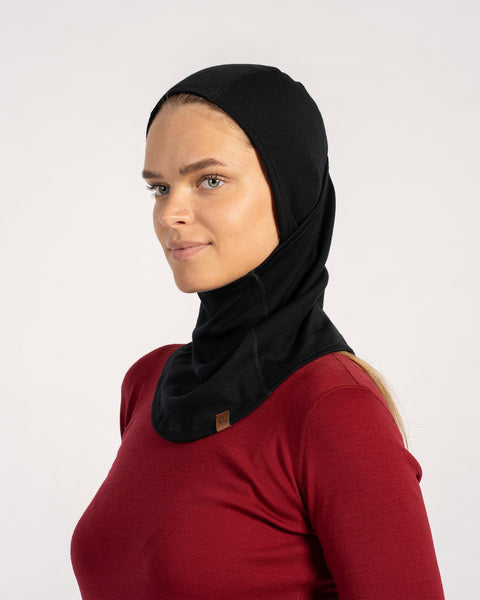 Side profile of woman in black Merino wool balaclava showing extended neck coverage, worn with a red top.