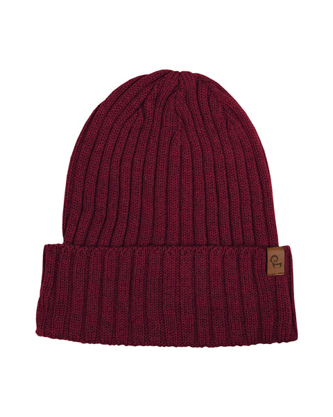A royal cherry ribbed knit beanie is displayed against a white background. The beanie has a folded brim and a small brown square tag is attached to the brim on the right side. The knit has vertical ribbing.