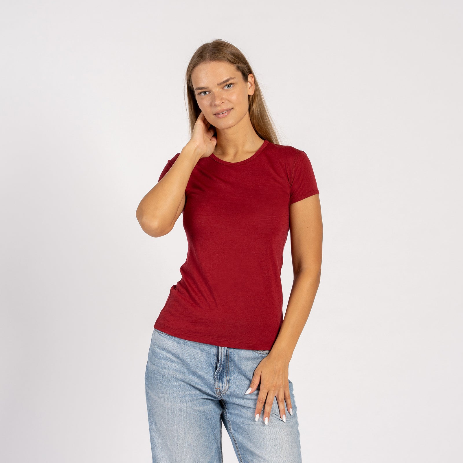Woman wearing a merino wool menique royal cherry t-shirt and denim jeans standing in white background.