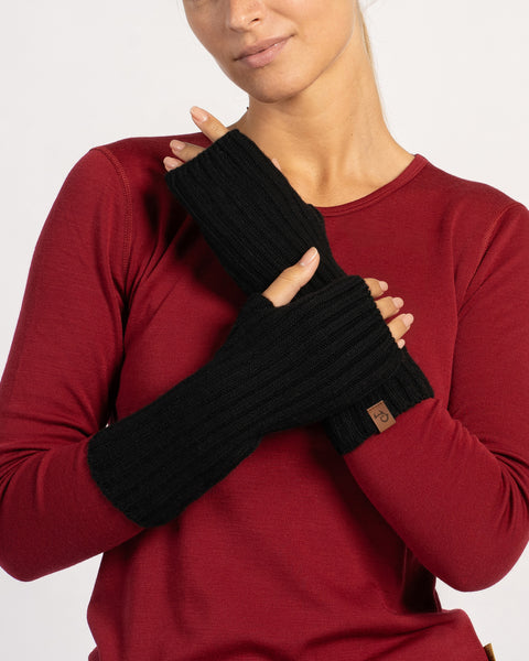 Close-up of long black ribbed wrist gloves on the model’s crossed hands against a red top.
