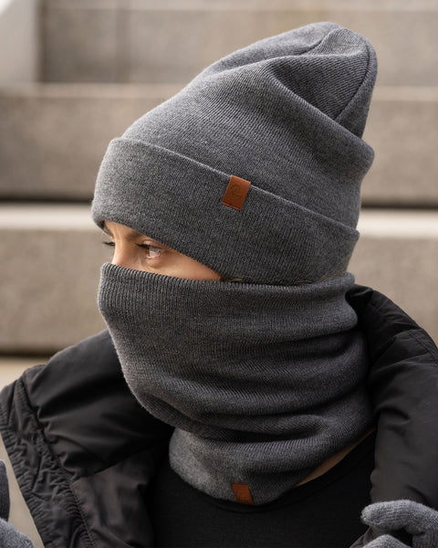 Woman wearing dark gray Merino wool knit neck gaiter and matching beanie, winter thermal face and neck warmer.