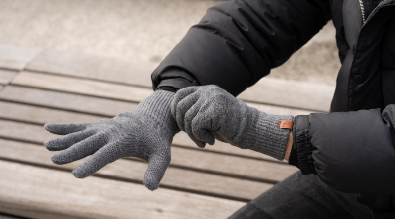 Man outdoors with dark gray knitted merino wool gloves.
