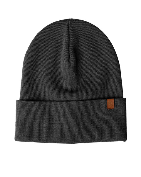 A dark gray knit beanie is displayed against a white background. The beanie has a folded brim and a small brown rectangular tag is attached to the brim on the right side. The knit appears to be a fine gauge.
