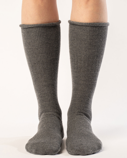 A woman wearing long merino wool socks in dark gray color.