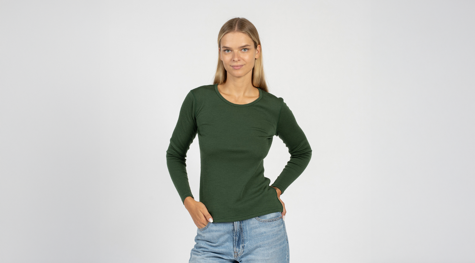 Woman wearing a green long-sleeve shirt and blue jeans on a white background