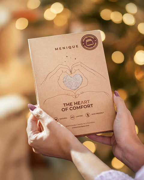 Menique product packaging held by hands with a blurred festive background