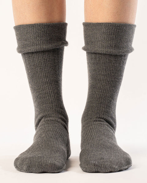 A woman wearing long merino wool socks in dark gray color, rolled down.